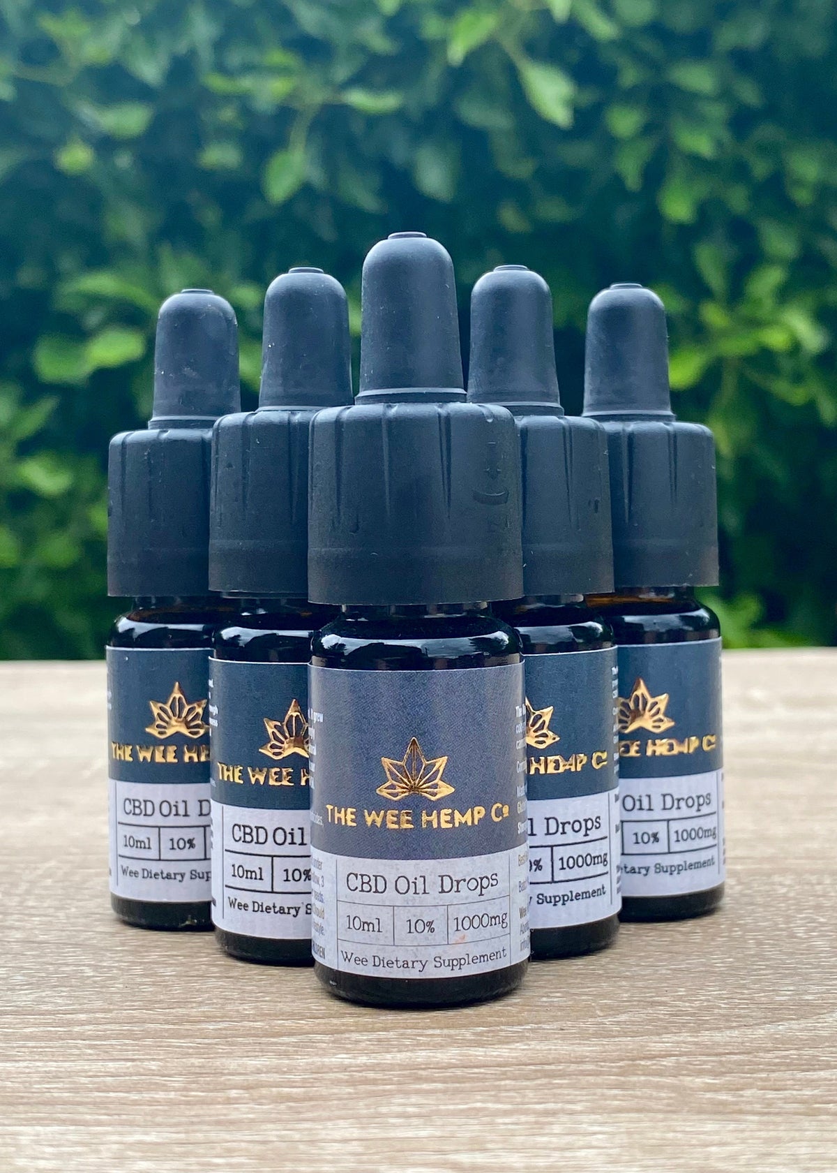 Bottles of Wee Hemp CBD Oil Drops on a wooden surface with a blurred green background.. Full Spectrum CBD Oil Drops - 10% | 1000mg - Hemp Oil | Vegan Friendly, Vegetarian Friendly | The Wee Hemp Company CBD Oil Shop | Wee Hemp CBD Oil Shop | Scotland's multi award winning CBD company | CBD Oil Shop | Cannabidiol drops | Aberdeen & Aberdeenshire | CBD Oil, CBD Balm, CBD Vapes E-liquid, CBD Cream, CBD Full Spectrum CBD Oil, Broad Spectrum CBD Oil, 3rd party lab tested CBD Oil
